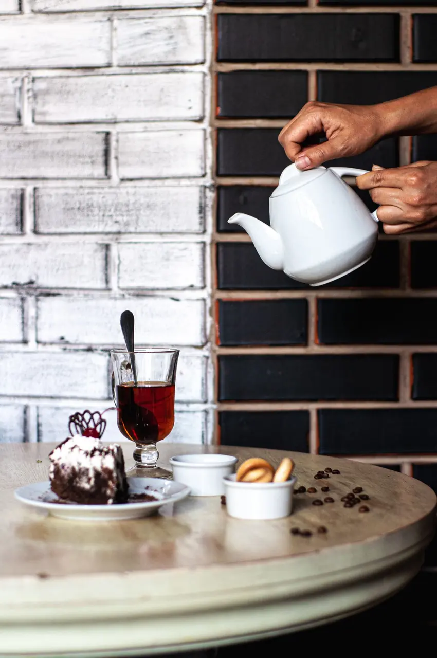 Freshly steeped loose leaf tea poured into fine ceramic teaware beside an artisan pastry