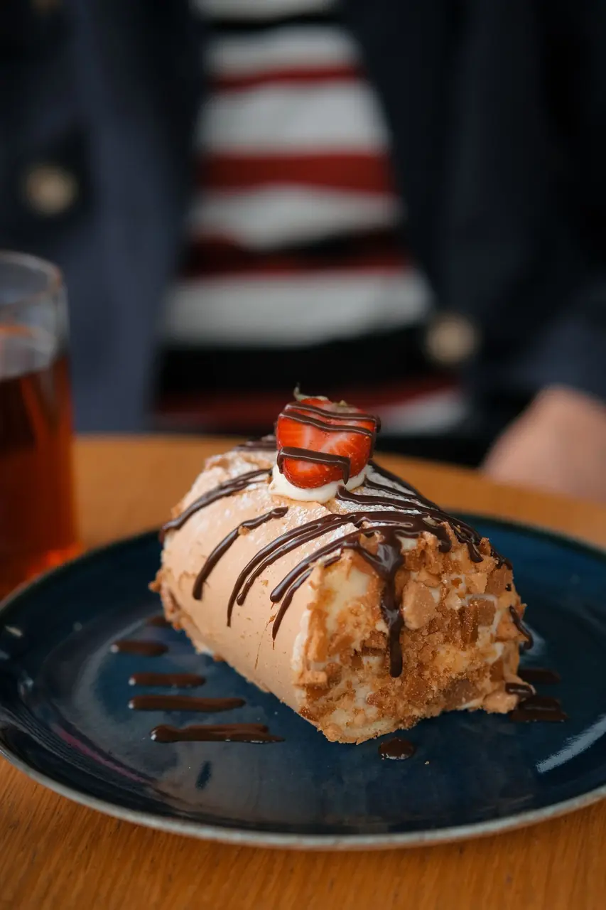 Artisan chocolate and hazelnut roulade slice garnished with fresh strawberry