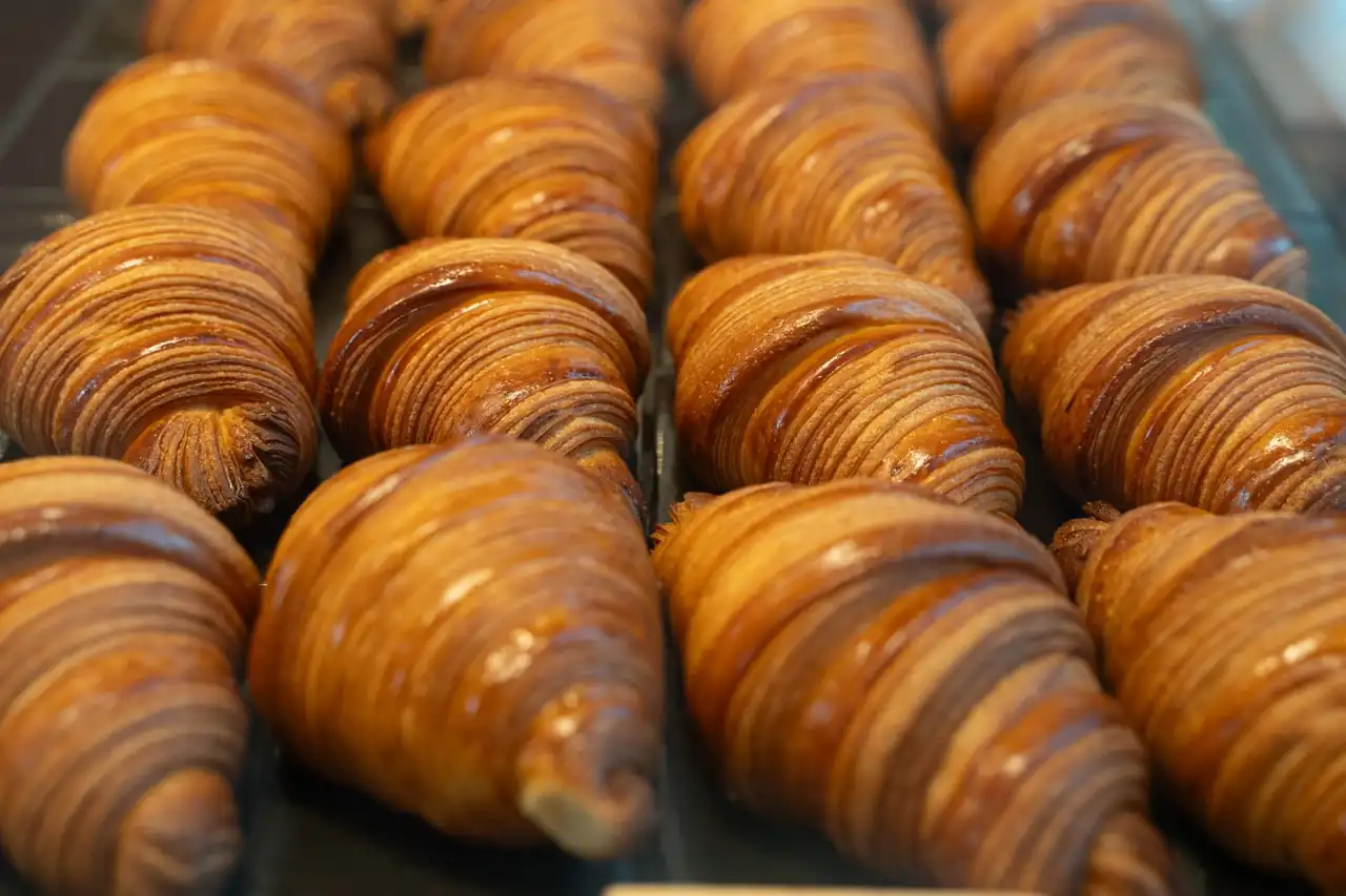 Freshly baked croissants lined up in an artisan bakery setting