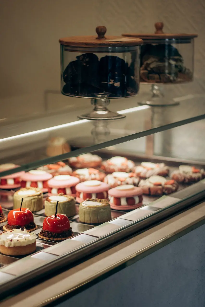 Glass vitrine showcasing delicate celebration cakes and layered gateaux