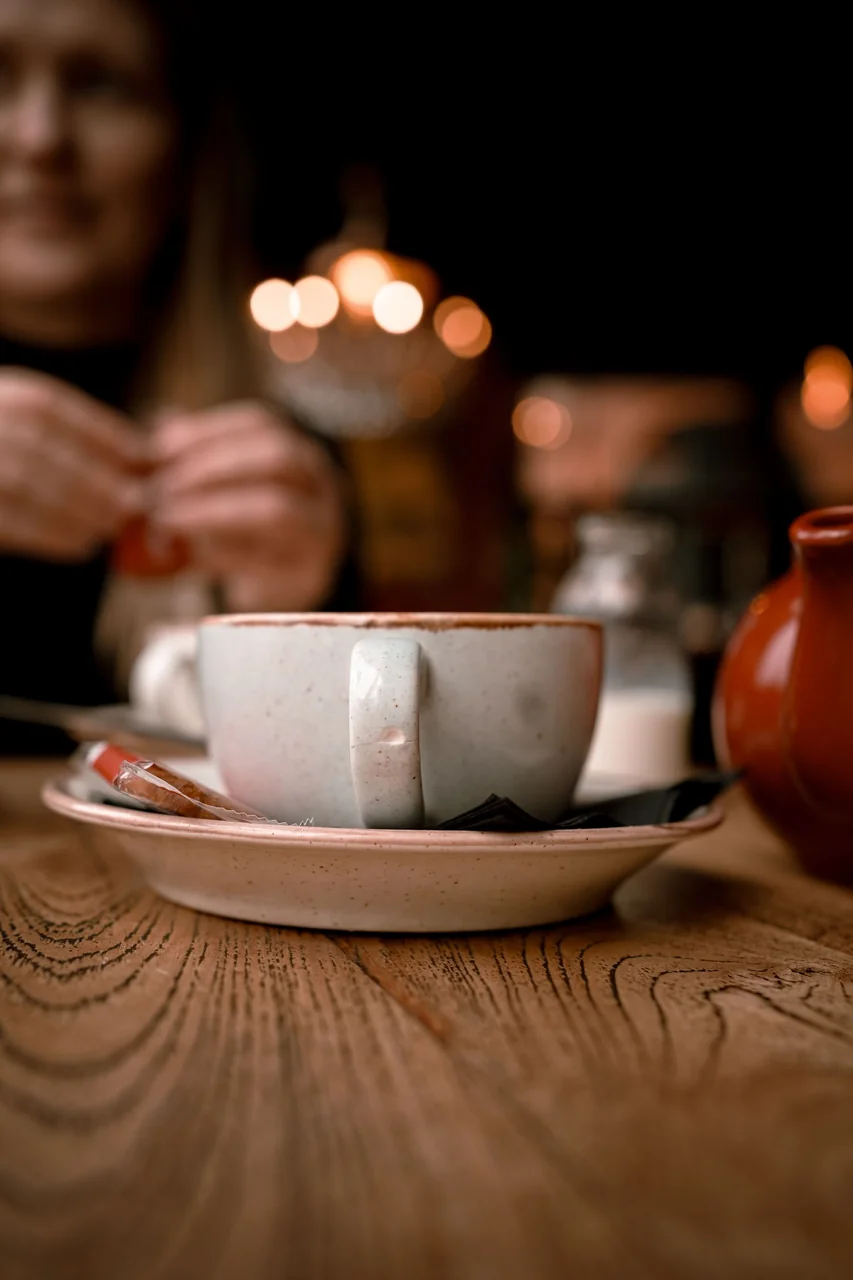 Teapot and ceramic cup set on a warm wooden café table